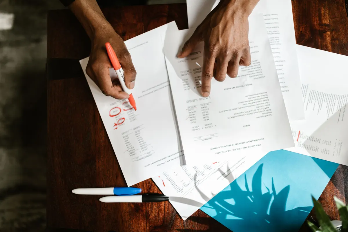 Hands highlighting lines on printed documents at a desk